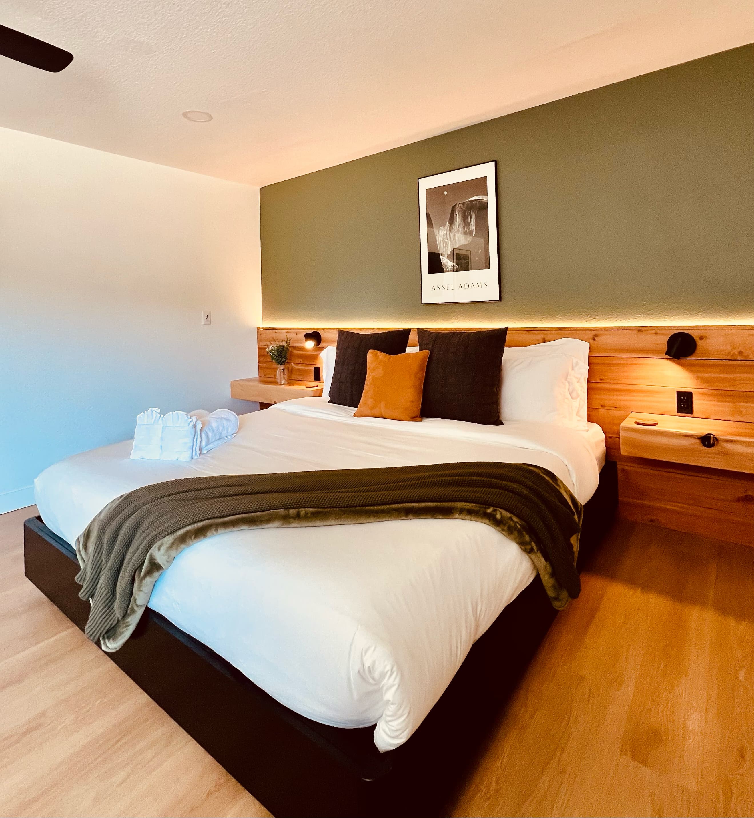 Guest room at Granite Ridge with a king bed, olive accent wall, and warm cove lighting