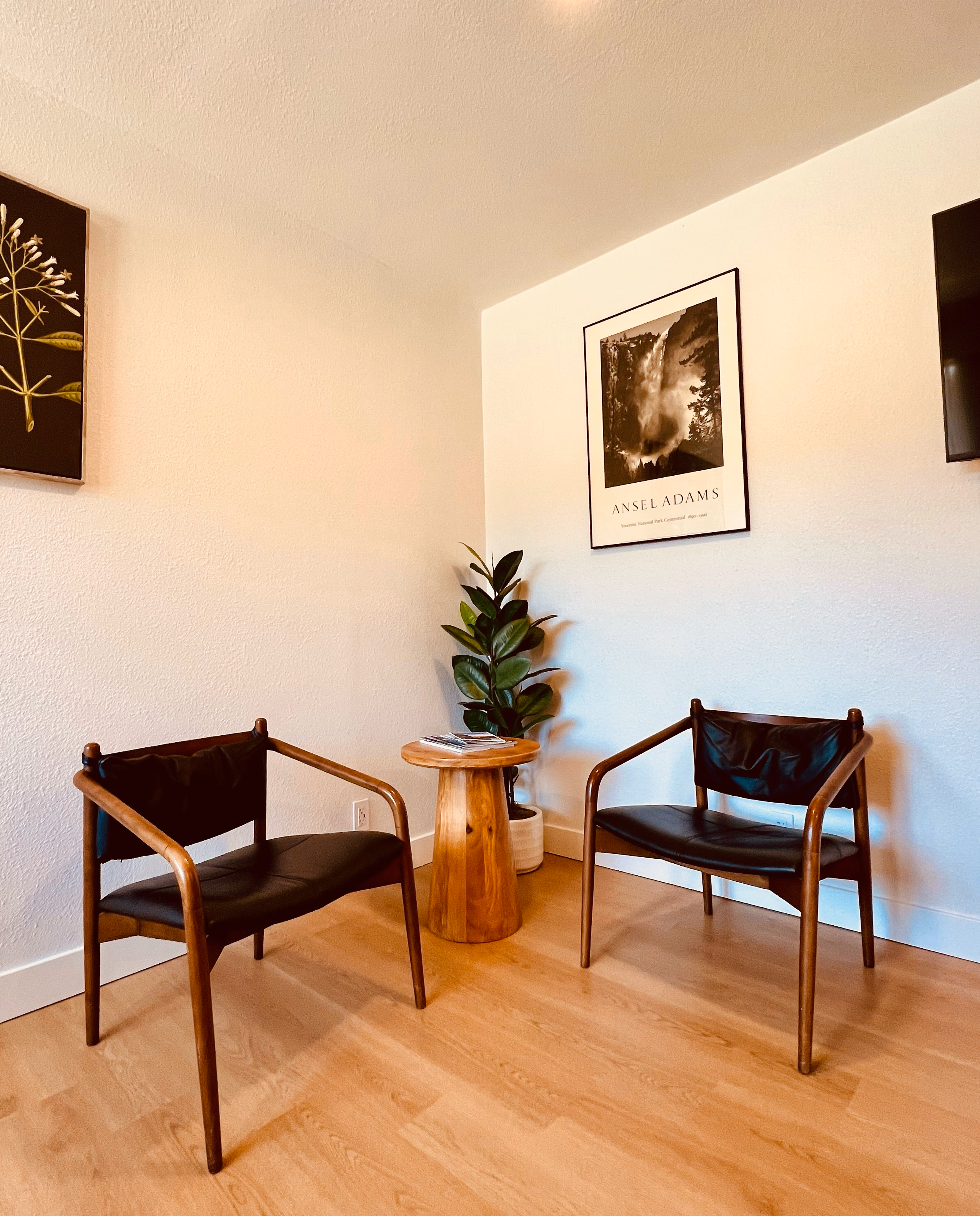 Sitting corner with two leather lounge chairs, a live-edge side table, and framed Yosemite prints